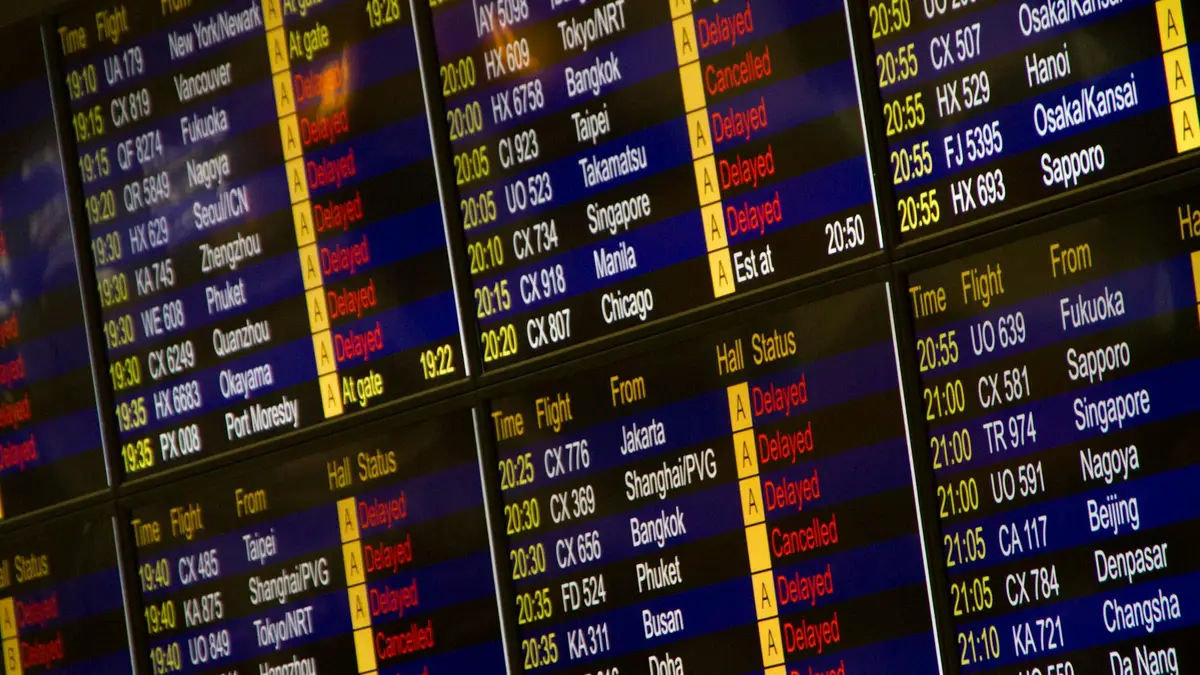 Panel de salidas del aeropuerto con varios vuelos marcados como retrasados o cancelados